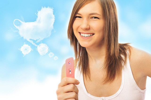 Portrait of young happy woman holding pregnancy test